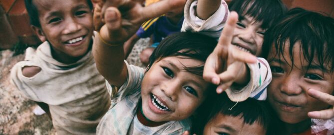 five children smiling while doing peace hand sign