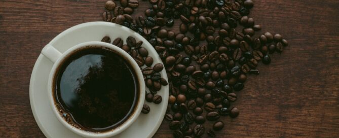cup of coffee surrounded by beans
